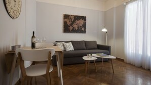 Een woonkamer met een bank, een kleine tafel, een stoel, een wereldbol kunstwerk en een klok aan de muur.