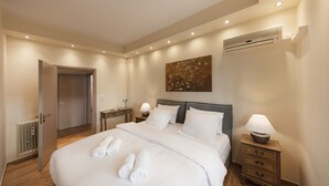 A modern hotel room with a large bed, bedside lamps, a radiator, and a painting on the wall. - Karneadou34 · Stylish Kolonaki 2 Bdr apartment (Athens)