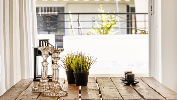 Mesa de madeira com duas plantas em vasos e dois castiçais.
