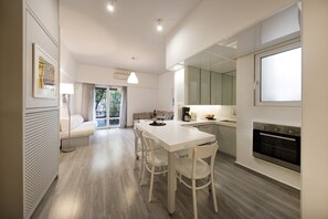 Een moderne keuken met een eethoek, witte kastjes en een inbouwoven.