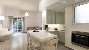 Een moderne keuken met een wit aanrecht, een inbouwoven en een eethoek met een witte tafel en stoelen.