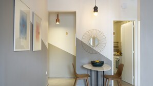 Un espace repas moderne avec une table ronde, deux chaises, un miroir décoratif et un escalier menant à une autre pièce.