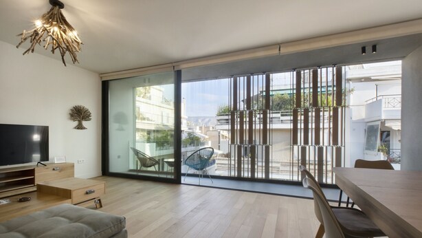 Un salon moderne doté d’un téléviseur à écran plat, d’un canapé, d’une table à manger avec des chaises et d’une grande porte-fenêtre coulissante donnant sur un balcon extérieur.