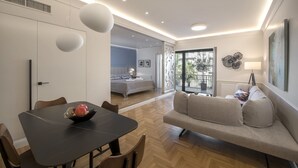 Ein modernes Wohnzimmer mit Essbereich, einer Couch und einem Bett im Hintergrund.