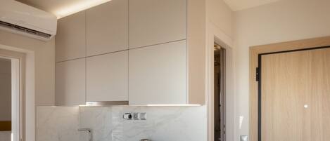 A modern kitchen with white cabinetry, a built-in oven, and a coffee maker.