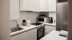 A modern kitchen with white cabinets, a stainless steel sink, a microwave, a coffee maker, and a Bosch refrigerator.