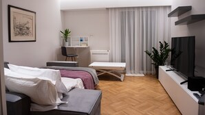 A modern living room with a sofa, a small table, a TV, and a plant.