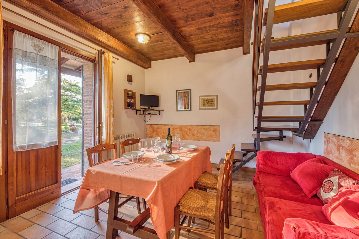 A dining area with a table set for four, a red sofa, and a wooden staircase.