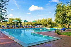 A swimming pool with blue lounge chairs and green umbrellas.