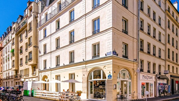 A multi-story building with a ground-level café and a visible storefront. - My Maison In Paris - Champ de Mars (Paris)