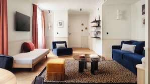 A modern living room with a sofa, armchair, and ottoman, a coffee table, and a leopard print rug. - My Maison In Paris - Champ de Mars (Paris)