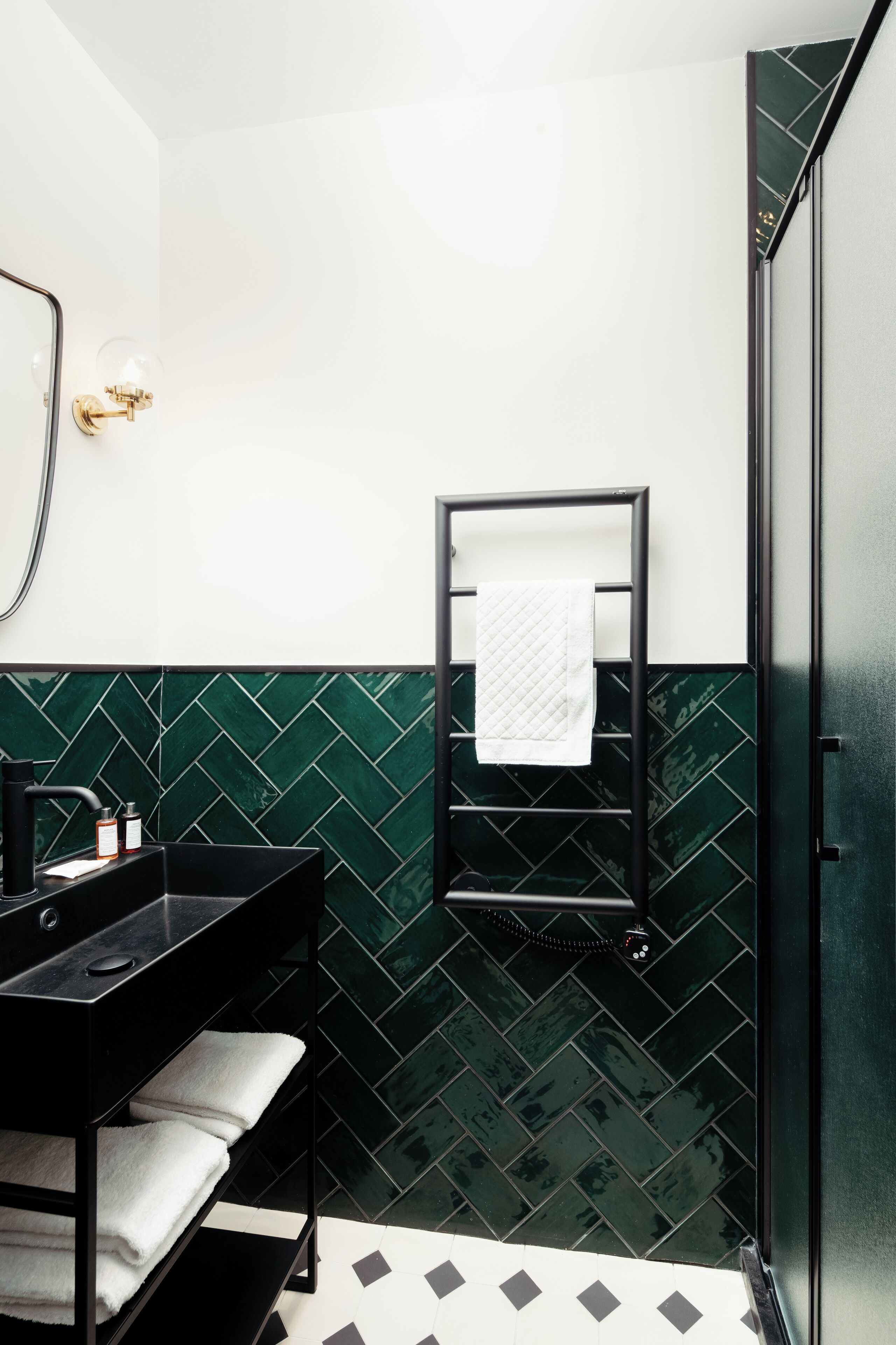 Une salle de bain avec un lavabo noir, un porte-serviettes et un miroir.