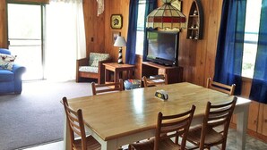 A wooden-paneled room with a dining table, chairs, a television, and a lamp. - D110- Large Private Saltwater Pool, 3 Bedrooms and Only 600 Yards to Beach!! (Duck)