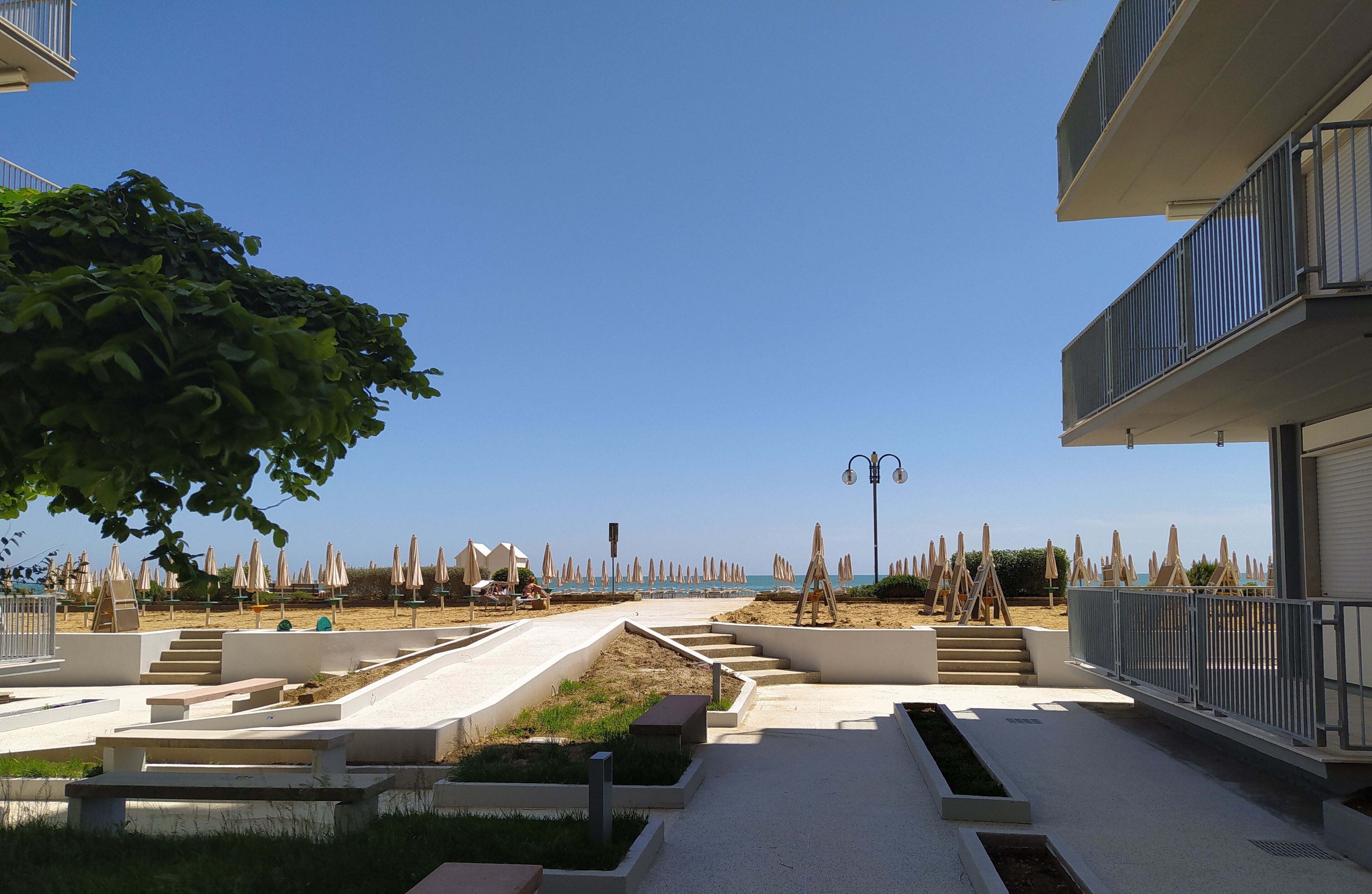 Ein moderner Außenbereich mit Pool, Treppen zu einem Strand und Strandstühlen.