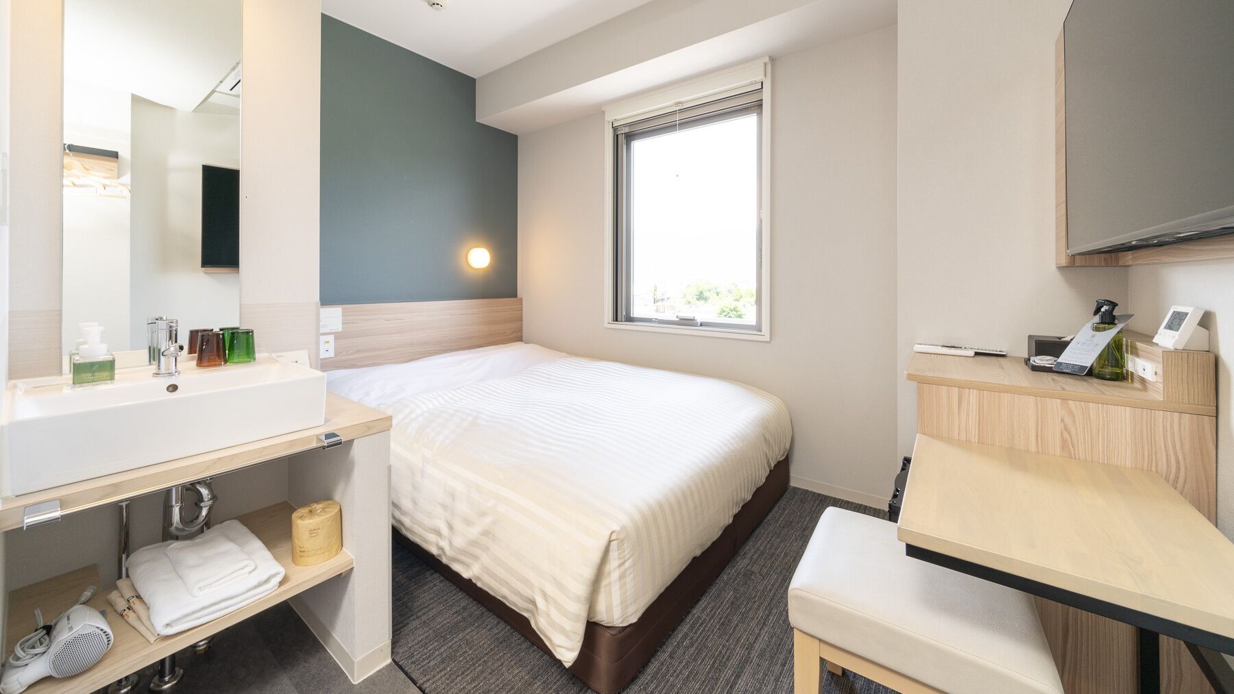 Une chambre d’hôtel comprenant un lit, un bureau, un miroir, une fenêtre et une salle de bain.