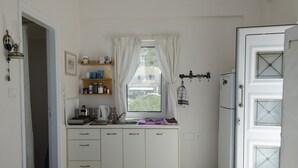 Cocina compacta con ventana, refrigerador y un pequeño comedor.