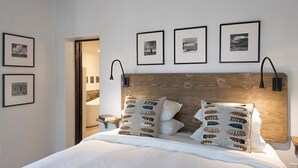 Ein Schlafzimmer mit einem hölzernen Kopfende, weißer Bettwäsche und mehreren gerahmten Bildern an der Wand.
