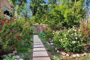 A garden pathway leading to a building with a stone facade.