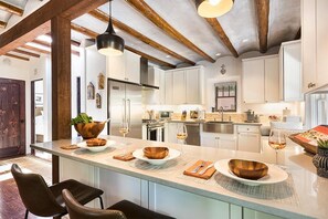 A modern kitchen with a central island, wooden cabinets, and pendant lighting.