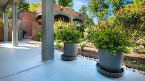 Ein überdachter Patio-Bereich mit Topfpflanzen und einem Gebäude im Hintergrund.