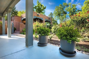 Un patio techado con plantas en macetas y un edificio al fondo.