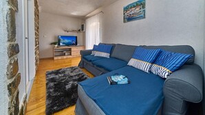 A cozy living room with a sofa set, a television, and a painting on the wall. - Villa with Private Jacuzzi (Šolta)