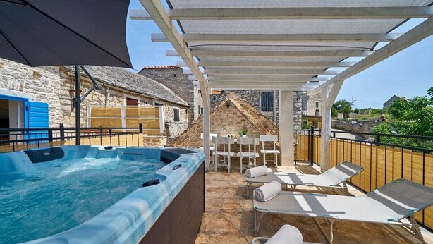 A hot tub area with stone flooring, white lounge chairs, and a pergola structure. - Villa with Private Jacuzzi (Šolta)