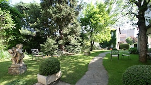 A garden with a stone pathway, benches, and a statue.