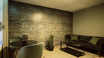 A modern living room with a brick wall, a round table with chairs, a sofa, and a coffee table.