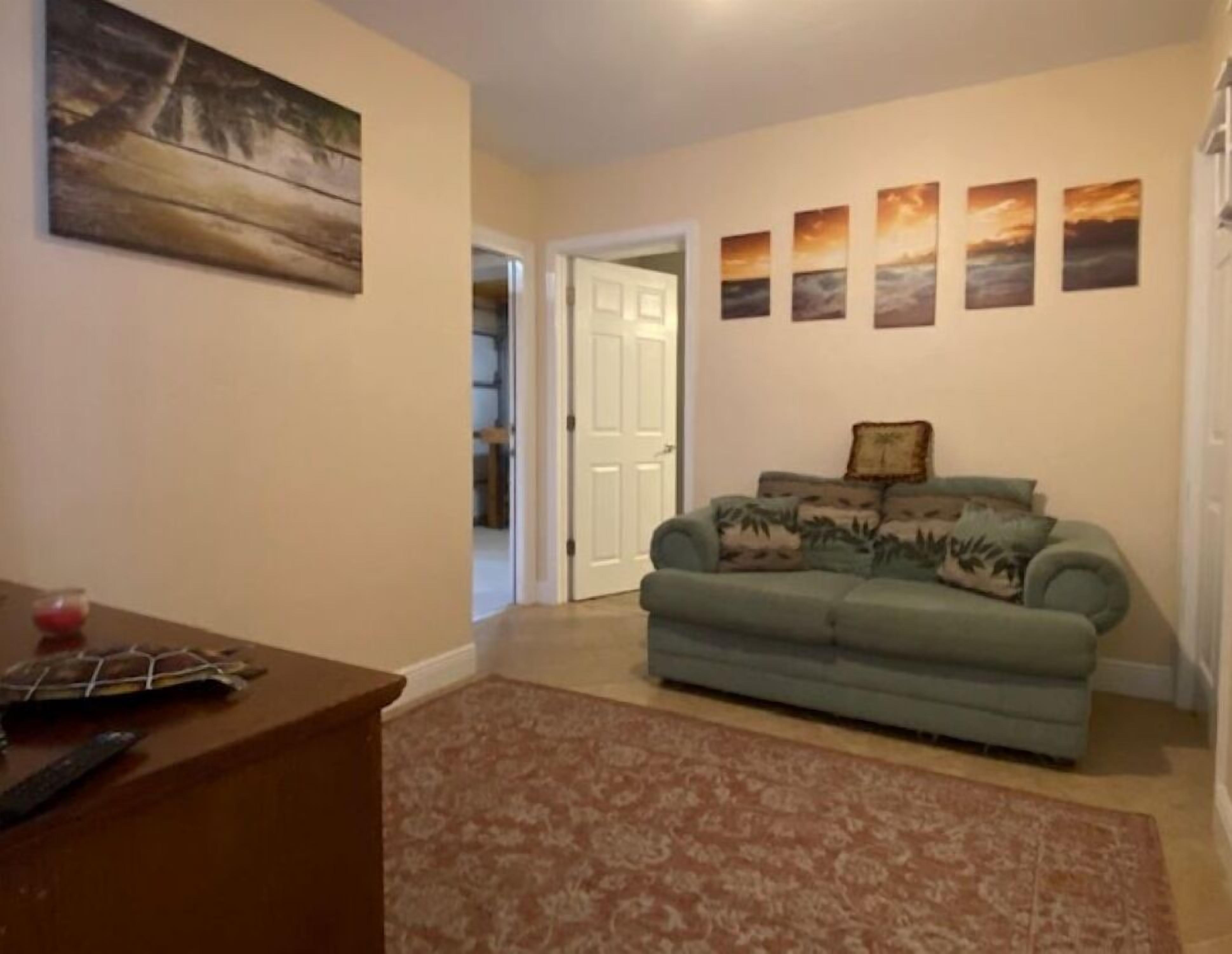 A living room with a green sofa, a patterned rug, and a painting on the wall.