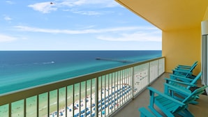 A balcony with turquoise chairs overlooking a beach with umbrellas and a pier. - Calypso TOWER 1! Gulf Front! No Obstructions! (Panama City Beach)