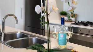 Ett modernt kök med en diskho i rostfritt stål, en vinflaska och ett glas.