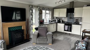 A compact living space with a fireplace, sofa, and a kitchen area including a stove and microwave. - Beautiful and Tranquil Lakeside Lodge - Sleeps 5 (Northampton)