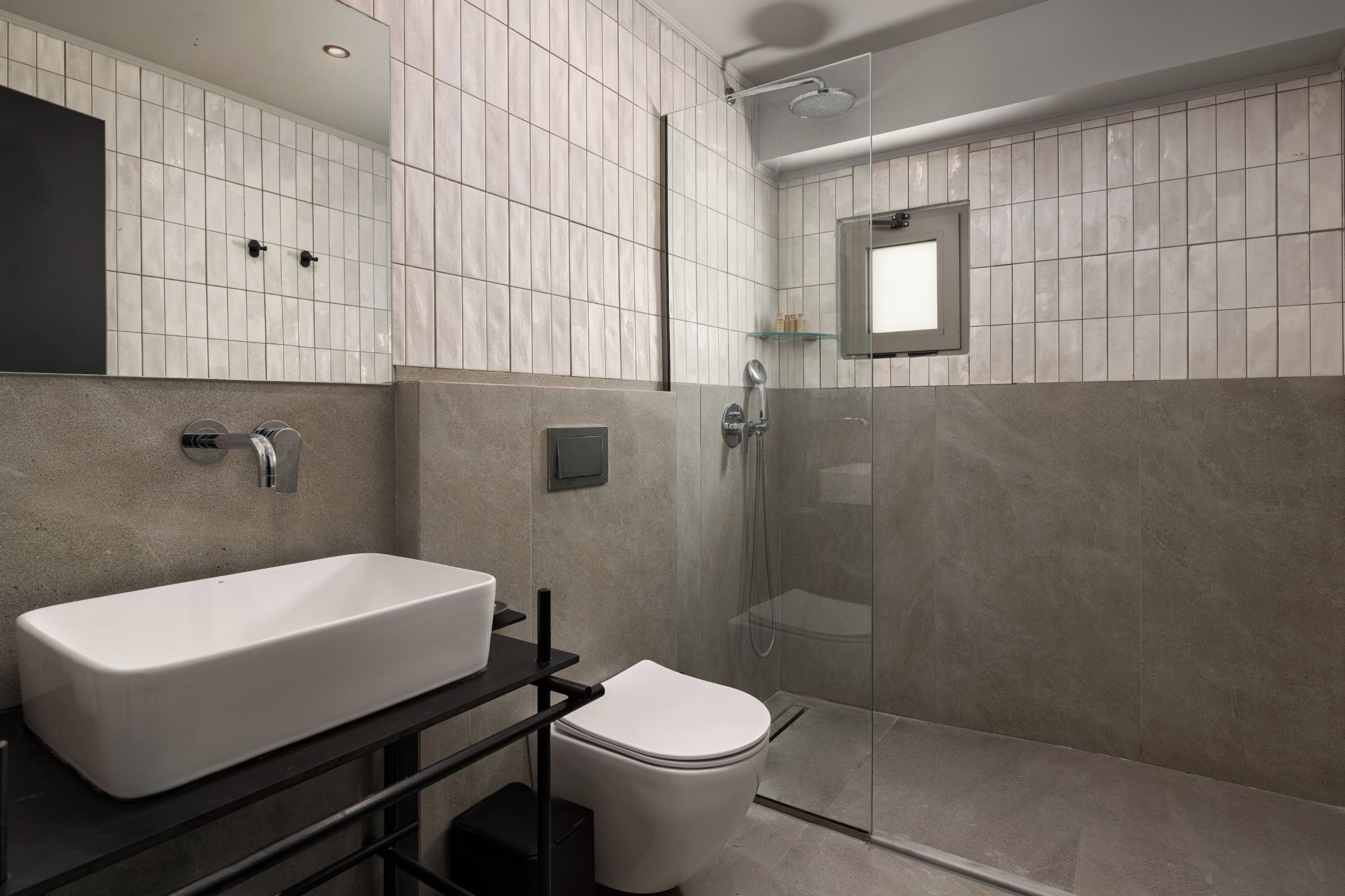 A modern bathroom with a white sink, toilet, and glass shower enclosure.
