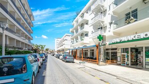 A street with parked cars, a pharmacy, and a building with balconies. - Santa Maria City Hotel (Rhodes)