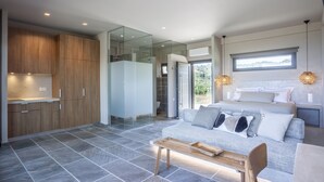 Une chambre à coucher moderne et bien éclairée, avec un grand lit, un canapé et un banc en bois.