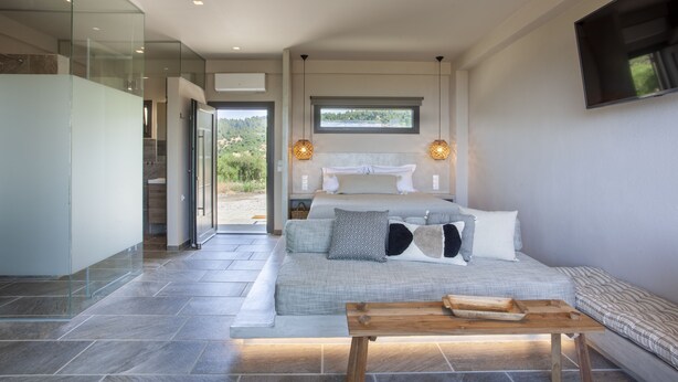 Une chambre moderne avec un grand lit, un canapé et un téléviseur fixé au mur.