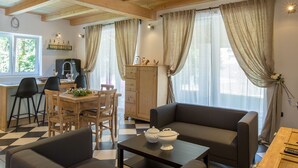 A cozy living room with a sofa, a dining table with chairs, and a kitchen area with a refrigerator.