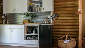 A compact kitchen with white cabinets, a stainless steel refrigerator, and a wooden wall. - The Love Shack (Wheatsheaf)