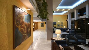 Un vestíbulo con un cuadro grande, una recepción, una zona de estar y una escalera.