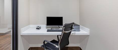 A modern office space with a white desk, a black office chair, a computer, and a telephone.