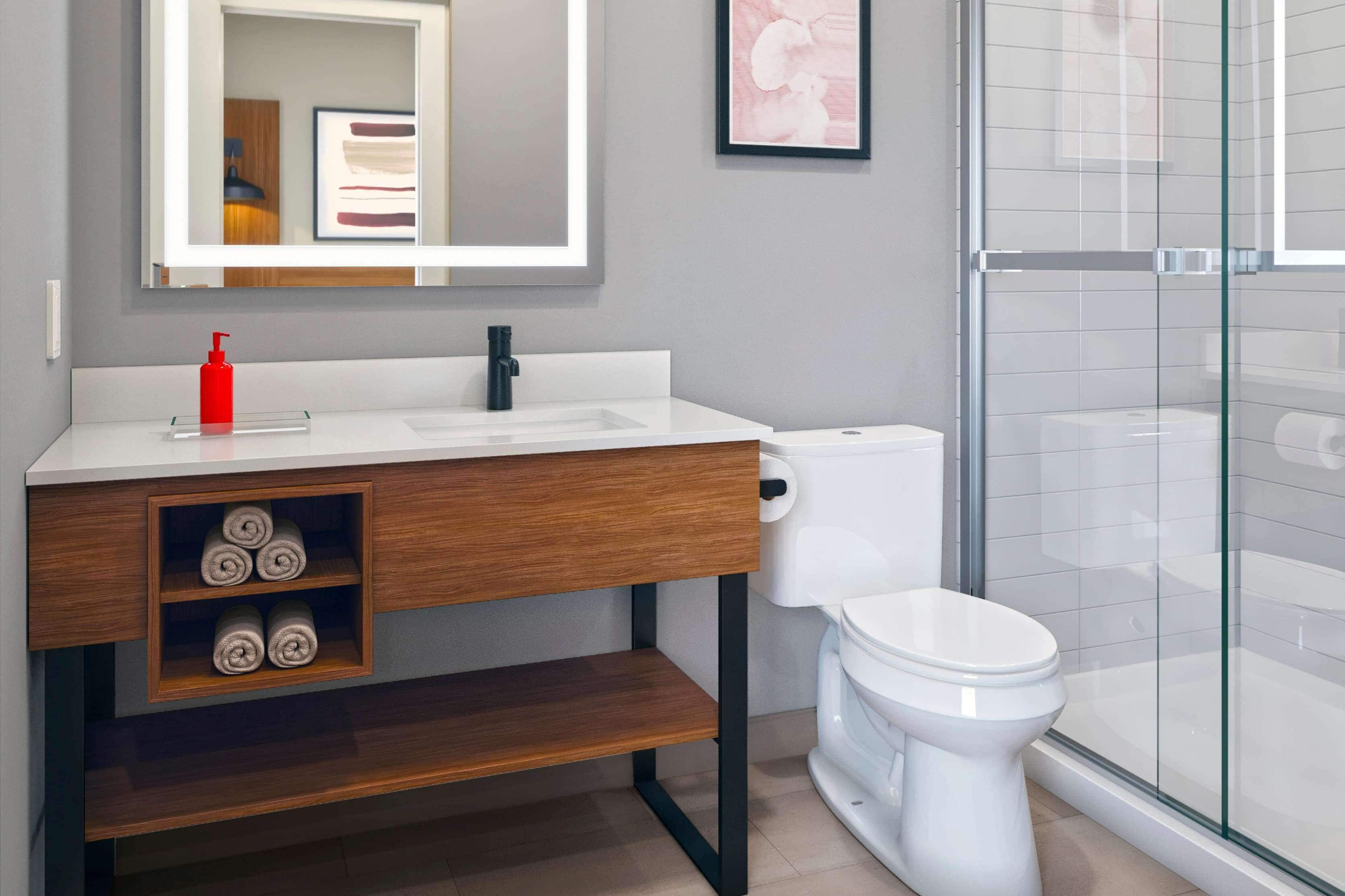Une salle de bain moderne avec un lavabo blanc, un meuble-lavabo en bois et une cabine de douche en verre.