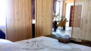 A hotel room with a bed, a small table with chairs, and a view of the outside. - Endless Blue/luxury Apartment (Kavala)