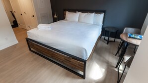 Habitación de hotel moderna con una cama grande, una mesita redonda y una pared de acento oscura.