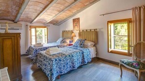 A bedroom with two beds, a wooden wardrobe, a window with curtains, and a ceiling with exposed beams. - Villa Llobiner, Perfect location! A country villa by Renthousing (Pollença)