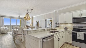 A modern kitchen with white cabinetry, a central island, a microwave, and a dishwasher. - Emerald Isle 504 - Front Row Beach chair service included! Affordable rates! (Panama City Beach)