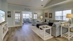 A spacious living room with a large TV, a sofa, a coffee table, and a fireplace.