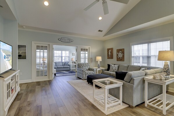 A spacious living room with a large TV, a sofa, a coffee table, and a fireplace.
