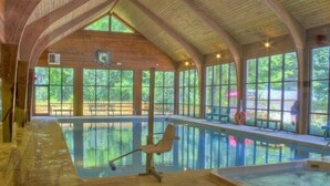 An indoor swimming pool with a wooden ceiling and large windows.