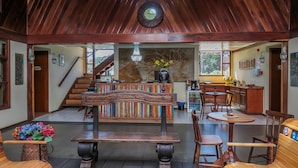 A spacious lobby with a wooden bench, a staircase, a bar area, and a dining setup. - Guida Residenza Pousada (Campos do Jordão)